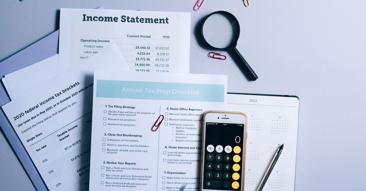 An organized desk with tax documents, checklist, and gadgets for tax preparation.