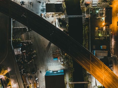 Aerial shot of a lit urban highway and industrial area at night.