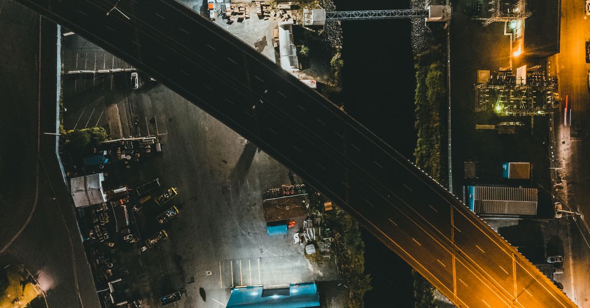 Aerial shot of a lit urban highway and industrial area at night.