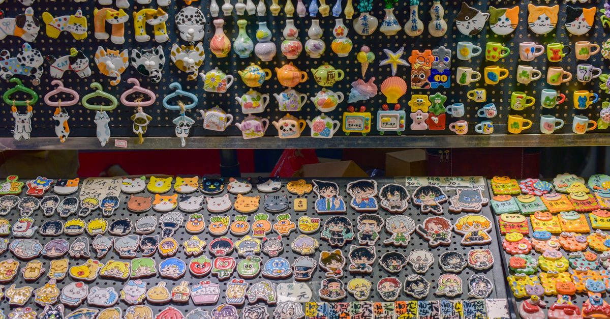 Vibrant handcrafted ceramic fridge magnets featuring animals, characters, and teapots on market display.