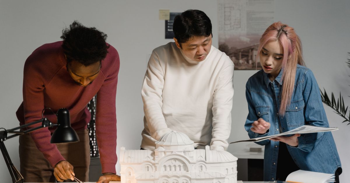 Architects discussing and planning a scale model in a modern office setting.