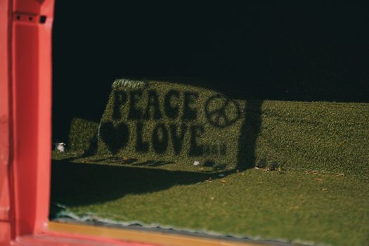 Creative shadow of 'Peace Love' sign with peace symbol on artificial grassmat