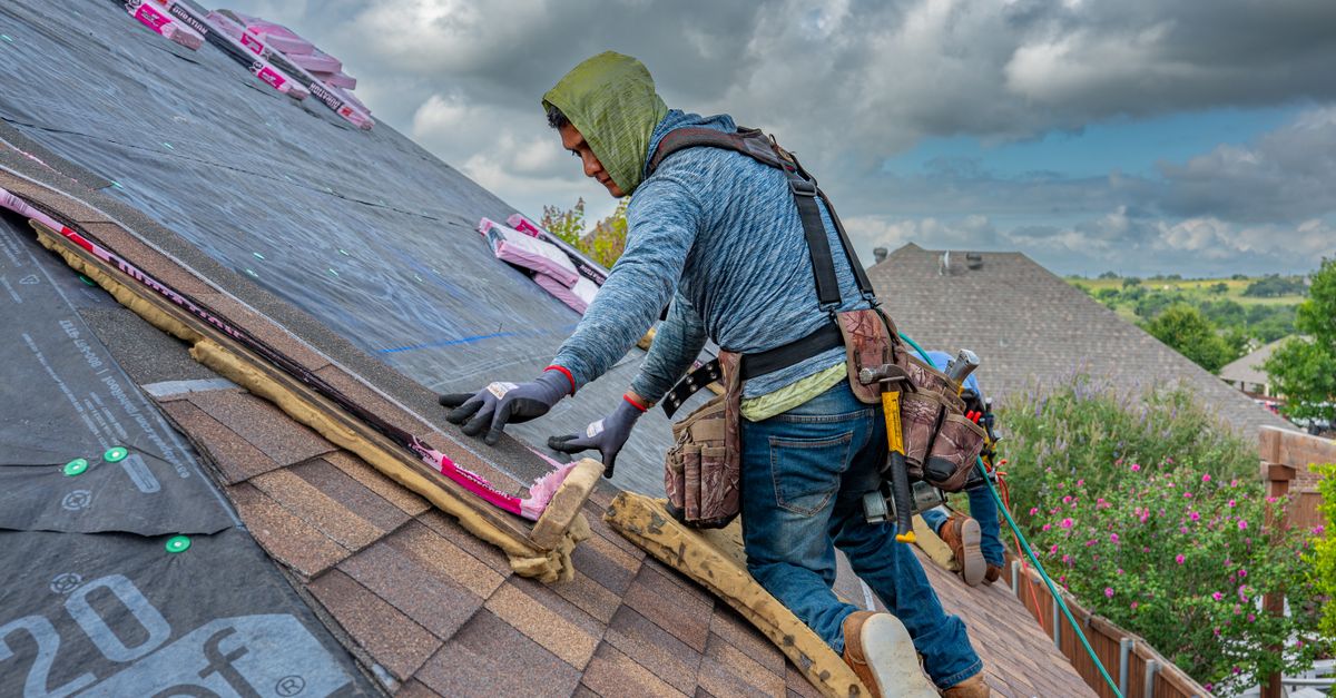 Roofers working on shingle installation on a home in Fort Worth, Texas under blue skies.