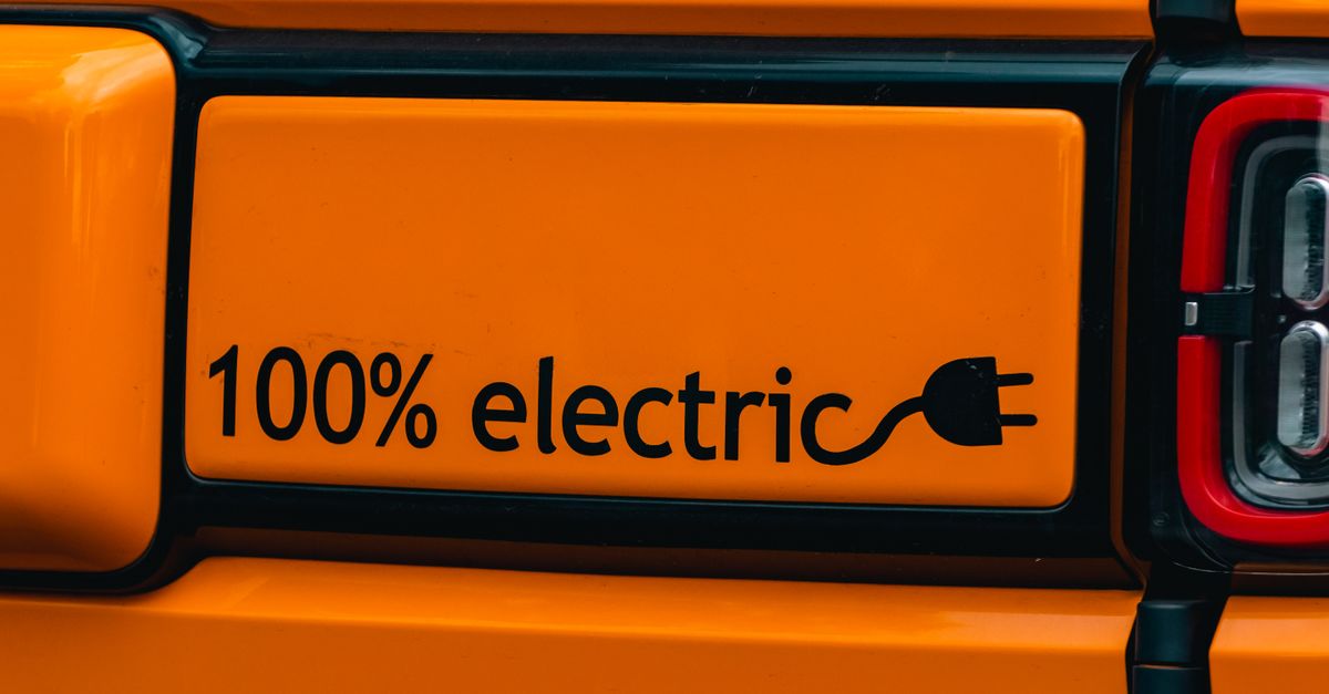 Vibrant orange electric vehicle with a '100% electric' emblem, showcasing eco-friendly transportation.