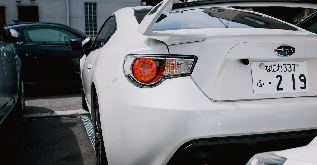 A stylish white Subaru BRZ parked in a city lot, showcasing its sporty rear design.