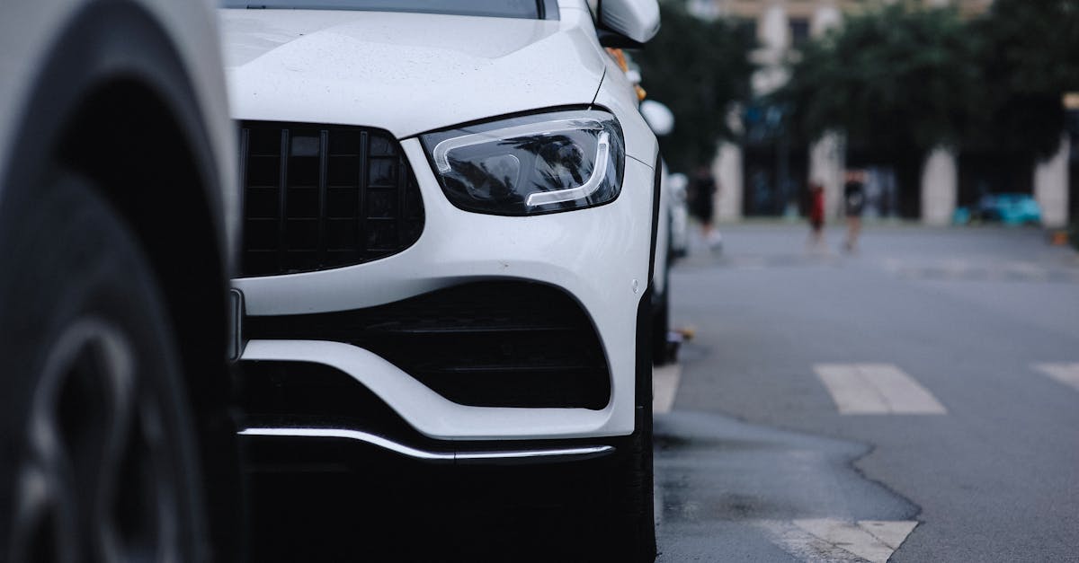 Close-up view of a sleek white car parked on a city street, reflecting urban style.