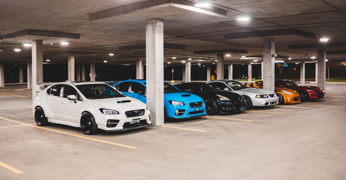 Bright new expensive automobiles placed on parking lot under concrete roof with bright lights