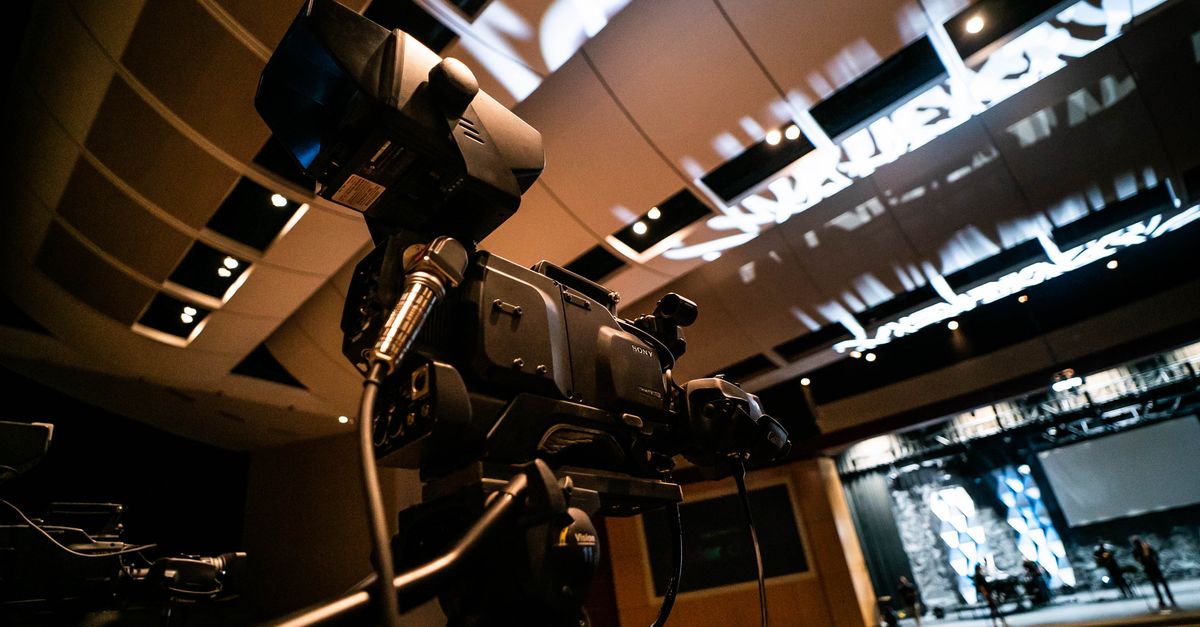 High-quality video camera set up in a modern indoor auditorium for recording or broadcast.