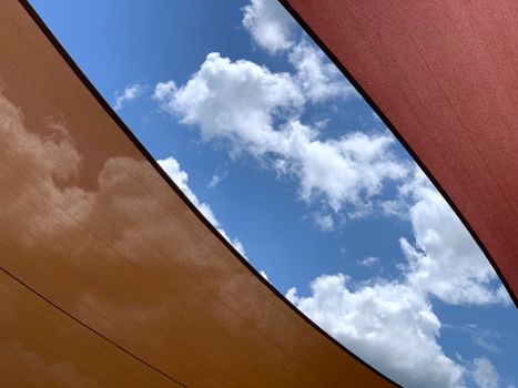 A striking abstract view of blue sky and white clouds framed by colorful canvas textures.