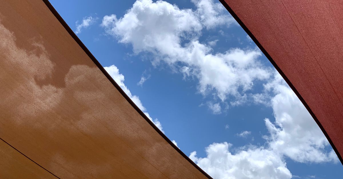 A striking abstract view of blue sky and white clouds framed by colorful canvas textures.