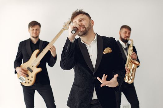 Energetic live band performance featuring musicians playing guitar, saxophone, and singing indoors.
