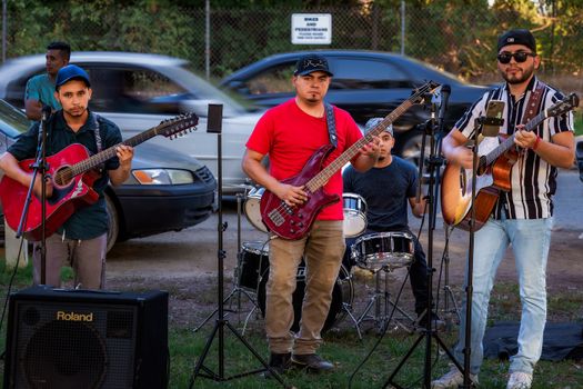 A group of musicians performing live on the roadside with guitars and drums, creating a vibrant street ambiance.