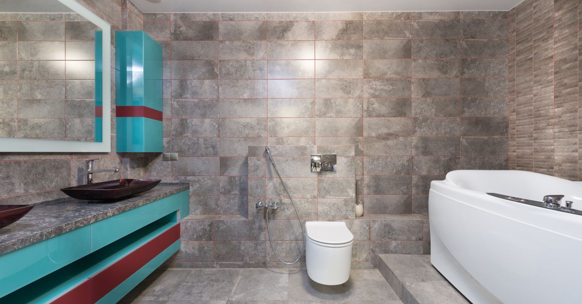 Interior of contemporary bathroom with modern toilet and bathtub with mirror hanging above sink