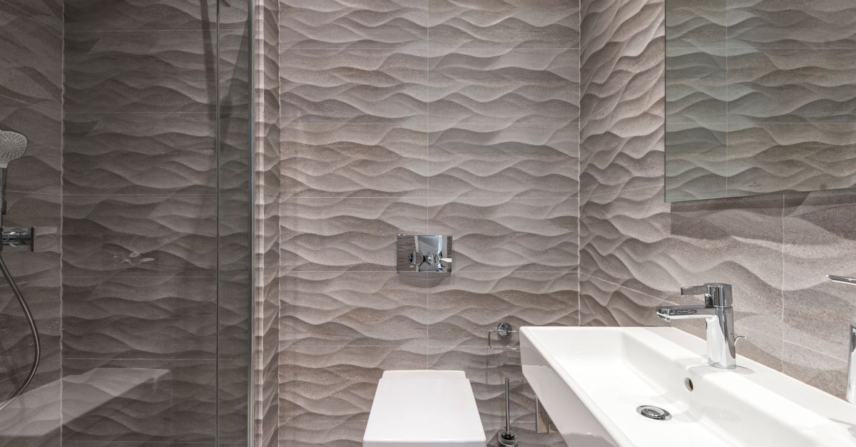 Sleek bathroom featuring textured walls, a glass shower, and a modern sink.