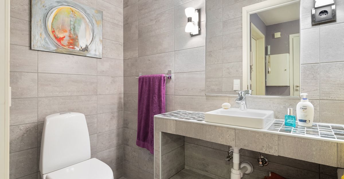 Elegant bathroom featuring contemporary design with clean lines, a toilet, sink, and artistic wall decor.