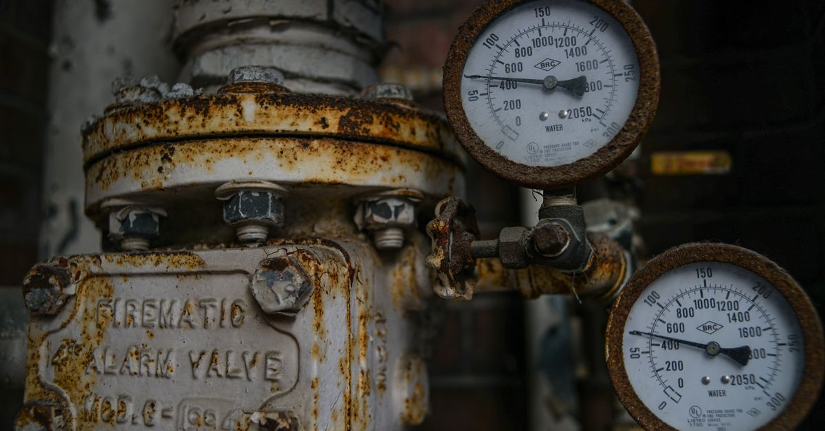 Close-up of an aged and rusted pressure valve with gauges showing readings.