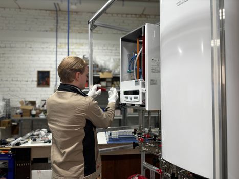 Technician inspects and repairs a heating system in an industrial workshop setting.