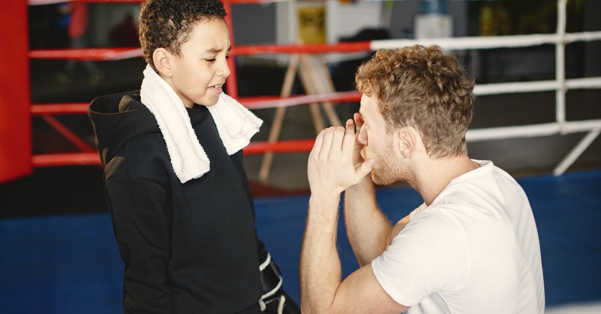 A young boy trains with a coach in a boxing ring, focusing on technique and determination.