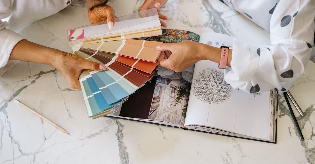 Two women in an office collaborating on color palettes for interior design planning.