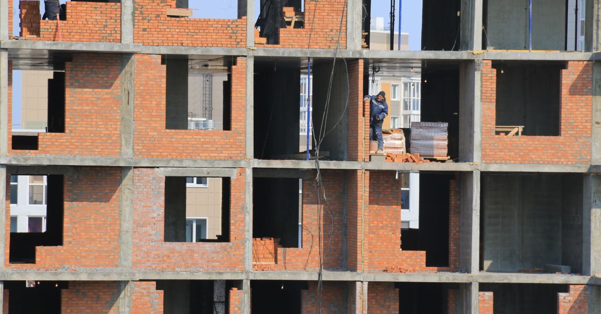 View of construction workers building brick walls on an unfinished urban apartment.