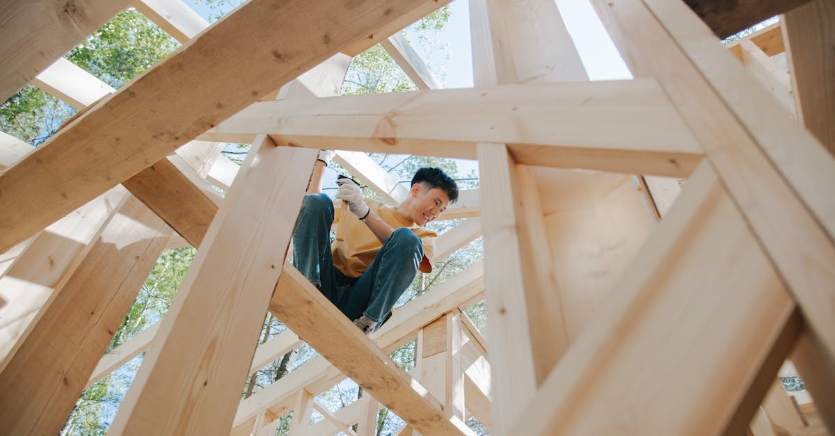 Carpenter working on the wooden structure of a house at a construction site under the sun.