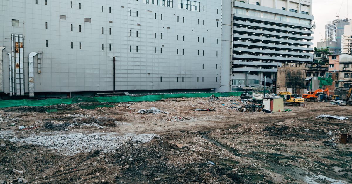A construction site with surrounding modern buildings in an urban setting.