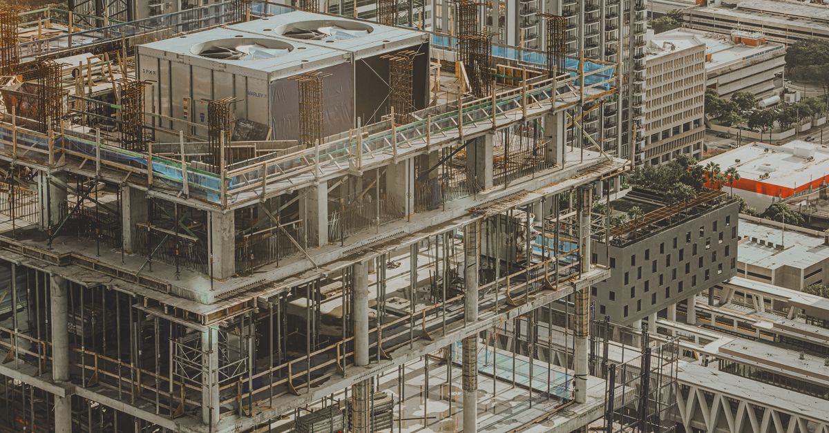 Aerial view of a high-rise building under construction in a bustling city environment.