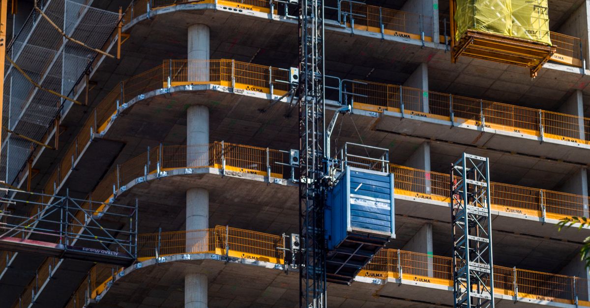 Detailed view of a high-rise building construction featuring a crane and multi-level scaffolding.
