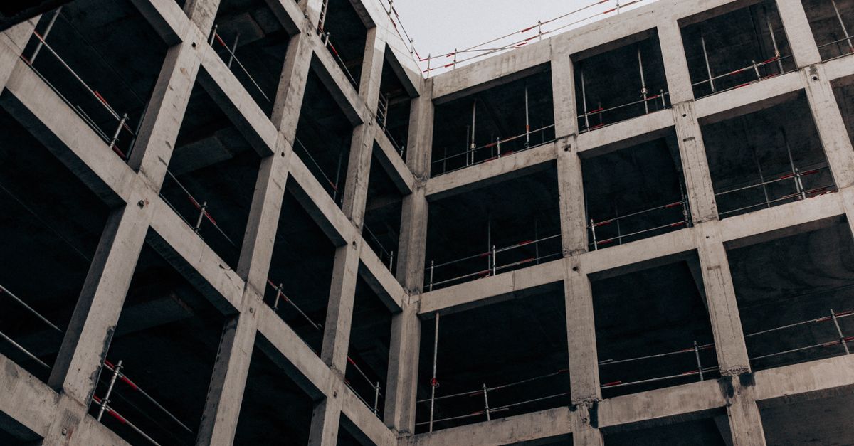 A low angle view of a modern concrete building under construction, showcasing its structure and design.