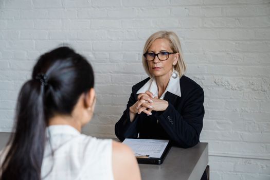 Professional businesswoman in a black blazer conducting an interview indoors.
