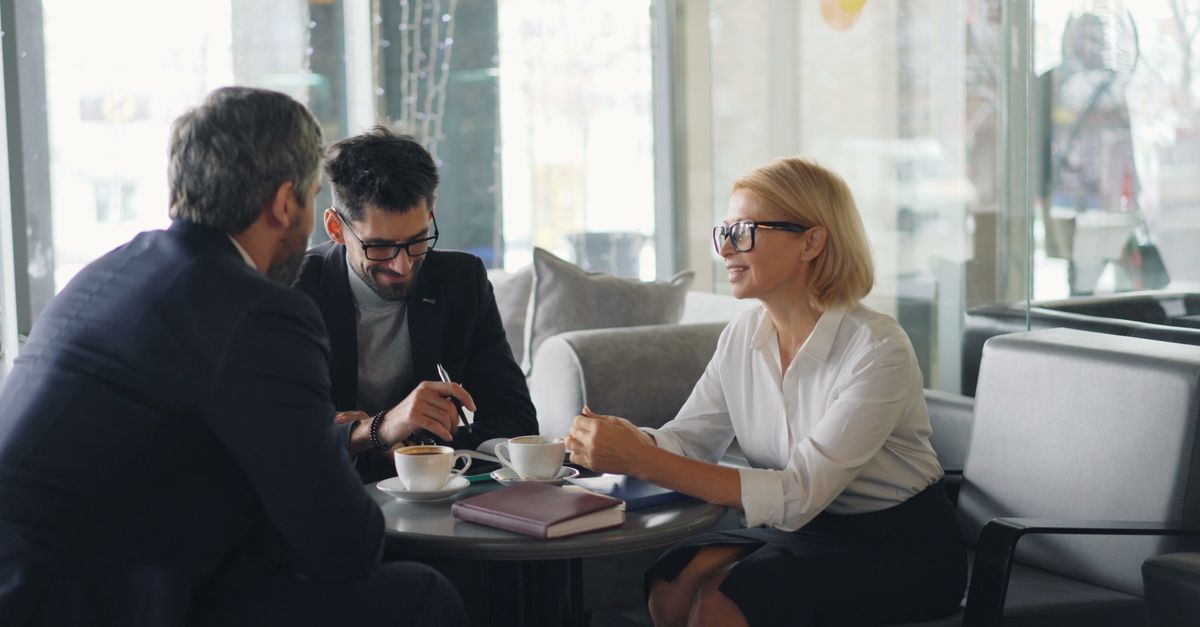 Three professionals engaged in a business meeting at a cafe.