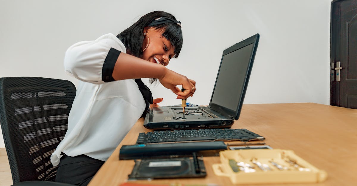 Woman repairing a laptop at a desk with tools, showcasing technology and skill.