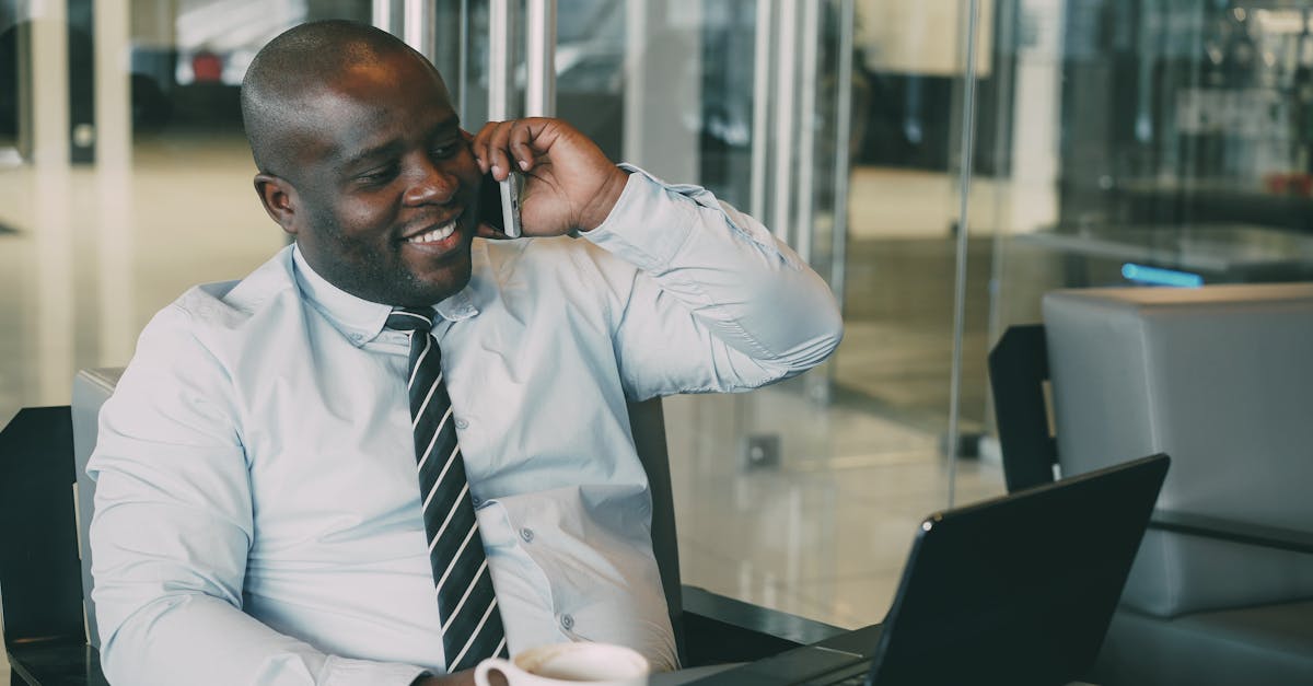 Smiling businessman talking on the phone while working on laptop in modern office.