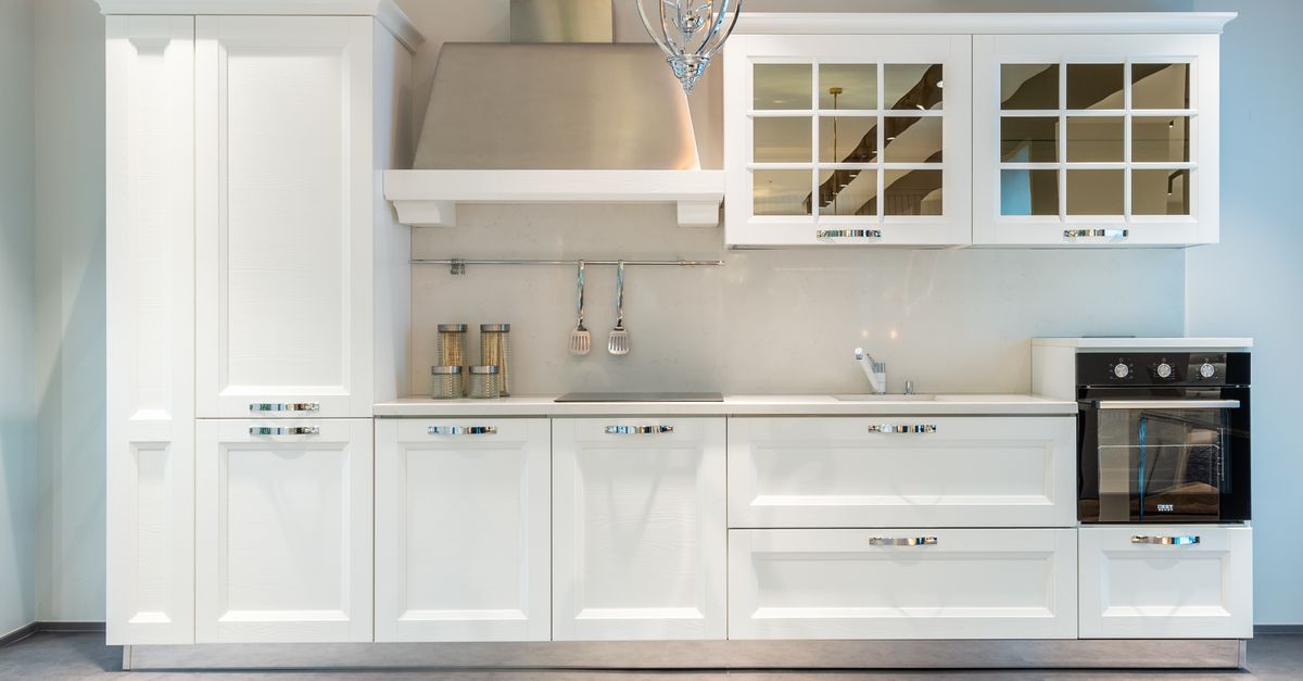 Interior of modern furnished kitchen with elegant white cabinets and contemporary appliances in spacious apartment