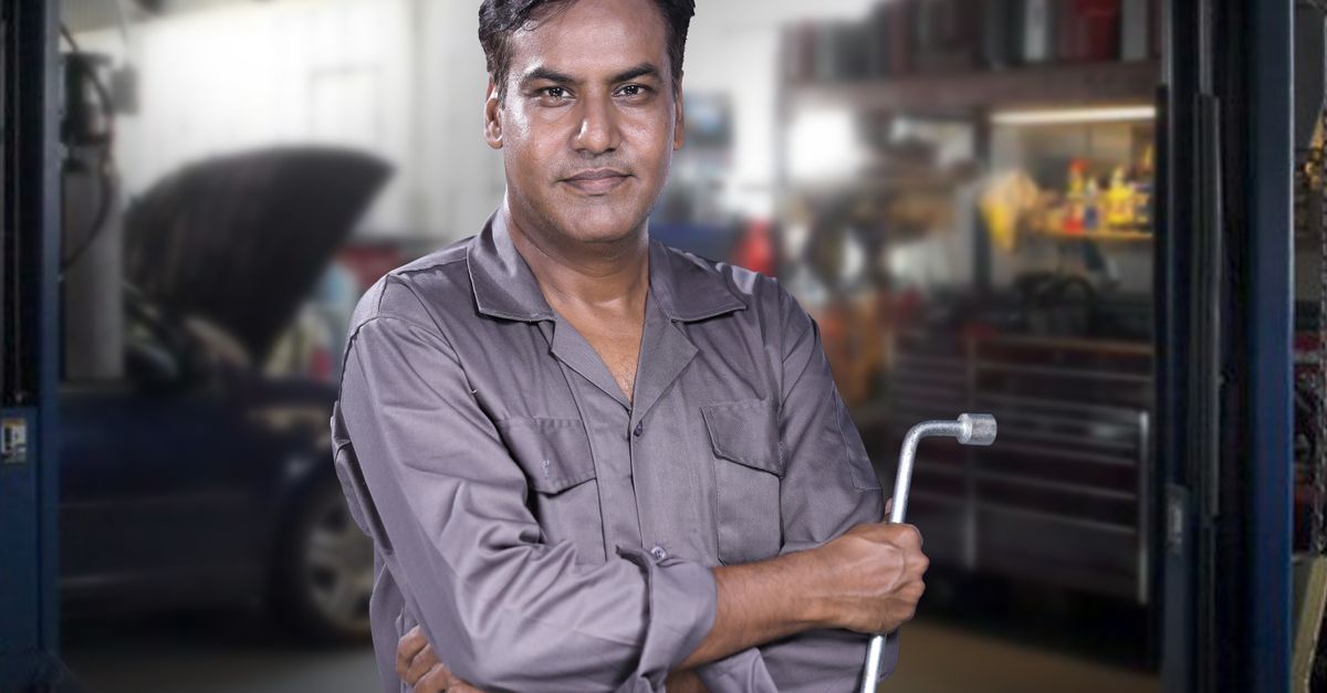 Portrait of a skilled mechanic holding a lug wrench in a Karachi auto repair shop.