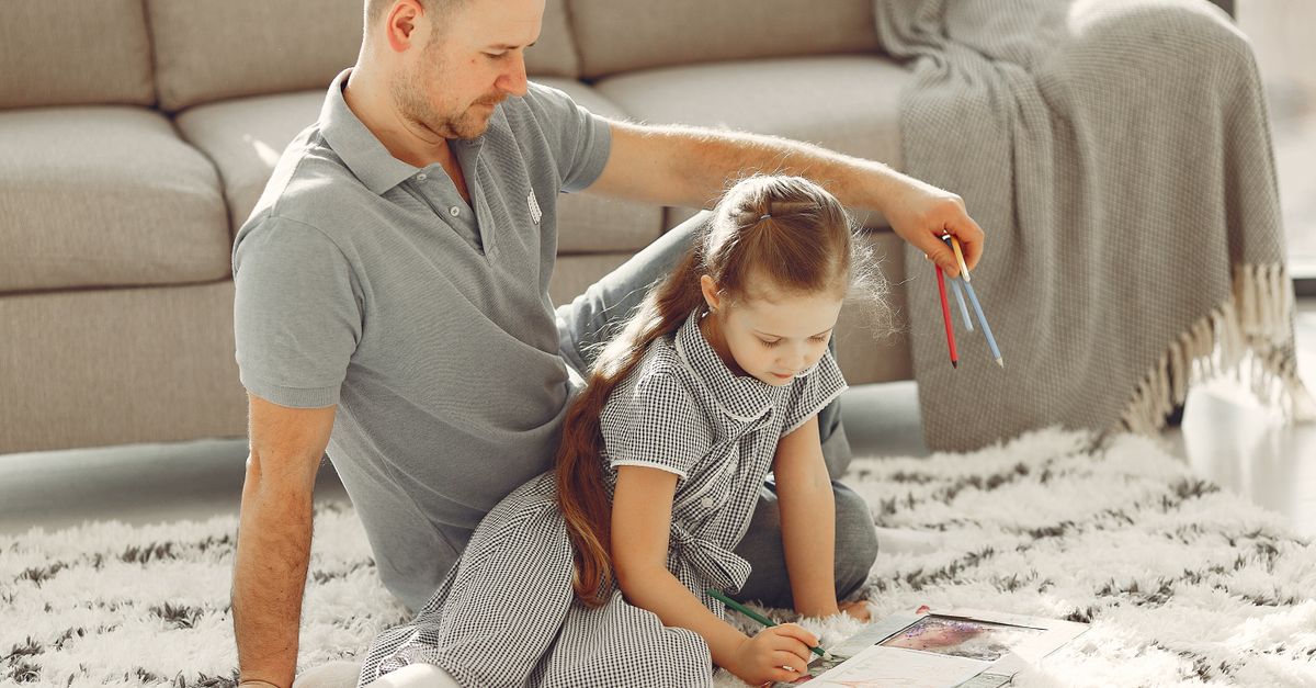 Father and daughter coloring together on the living room floor, enjoying quality time.