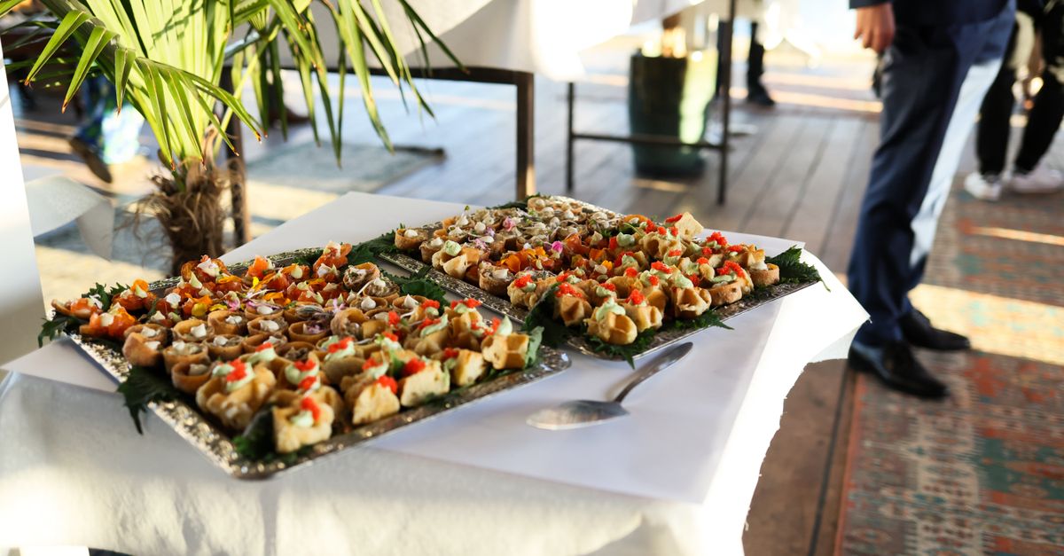 Gourmet appetizers at a stylish indoor event with attendees in formal attire.
