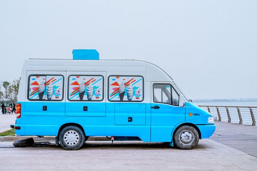 Bright blue ice cream van parked by a scenic waterfront, ideal for summer imagery.