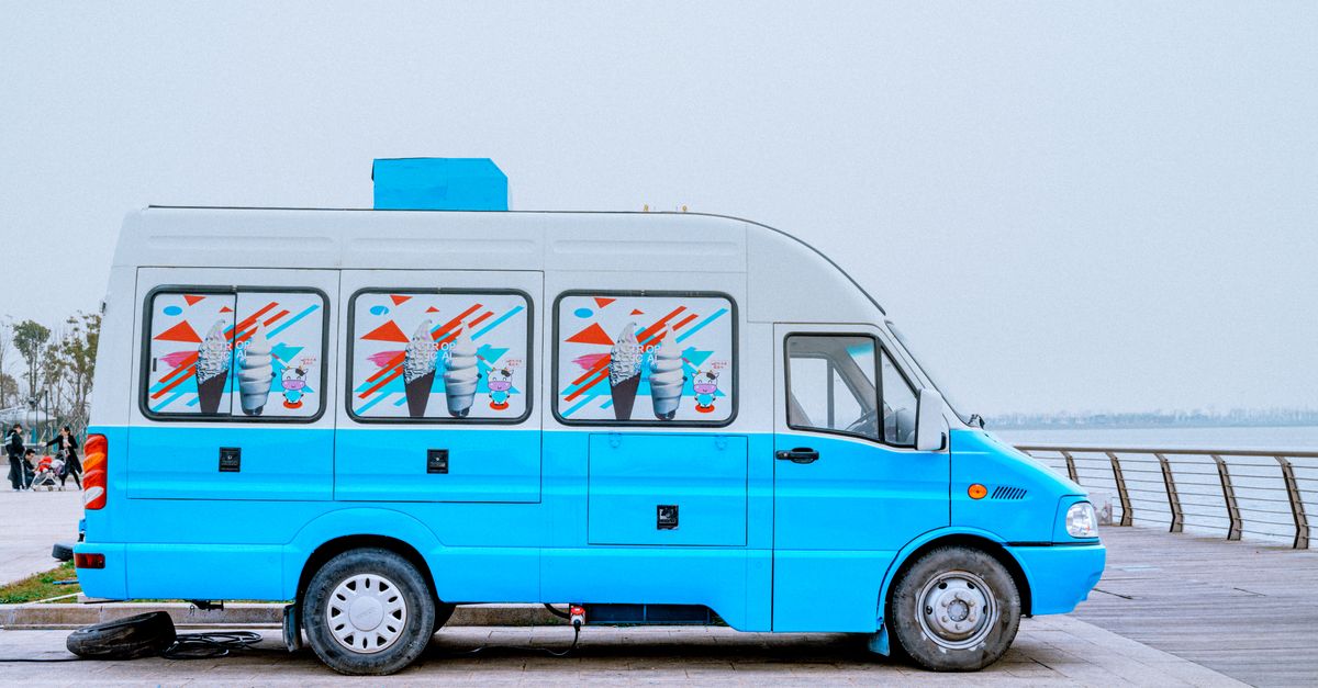 Bright blue ice cream van parked by a scenic waterfront, ideal for summer imagery.