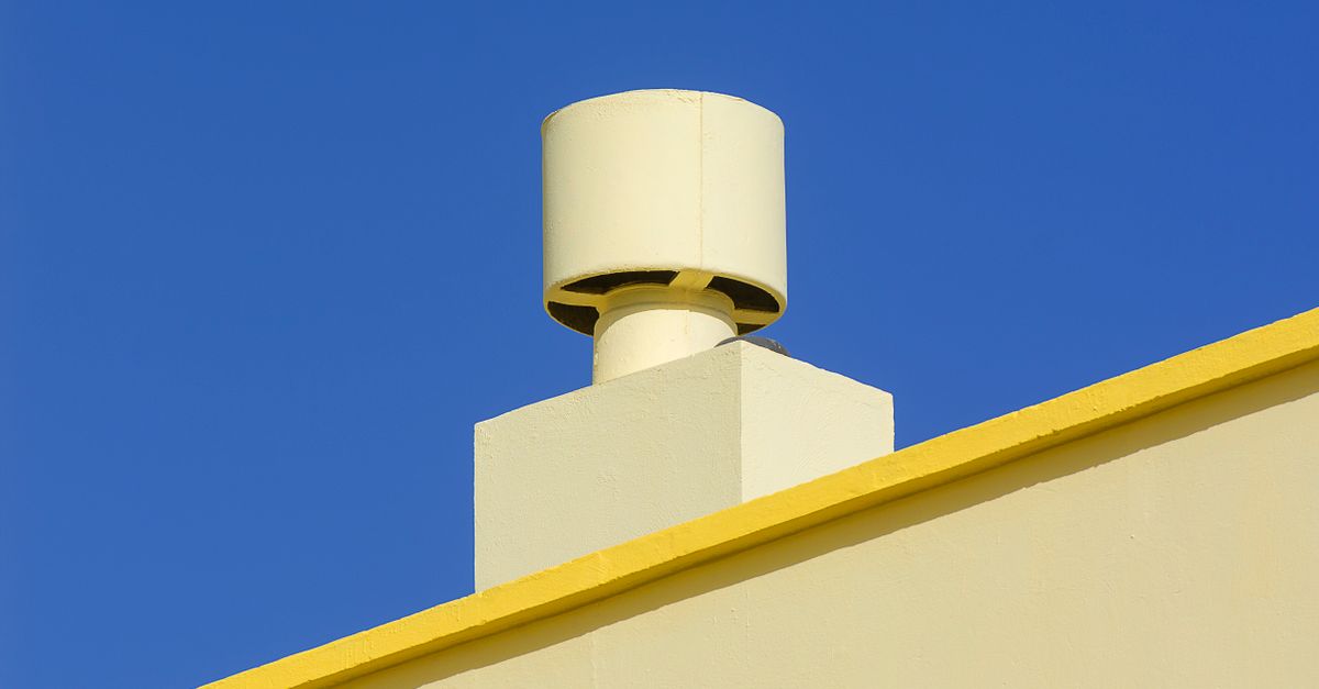 Yellow industrial chimney against a vibrant blue sky, representing modern architecture.