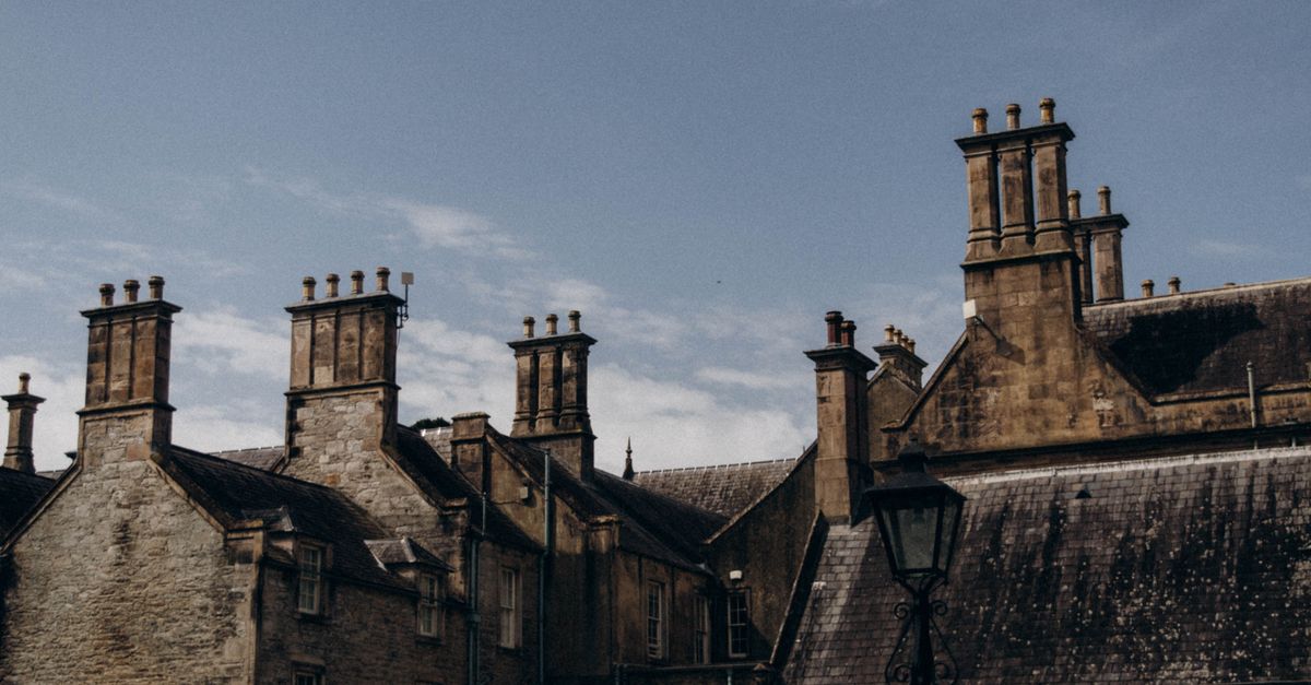 A captivating view of historic Gothic brick buildings with tall chimneys under a clear sky.