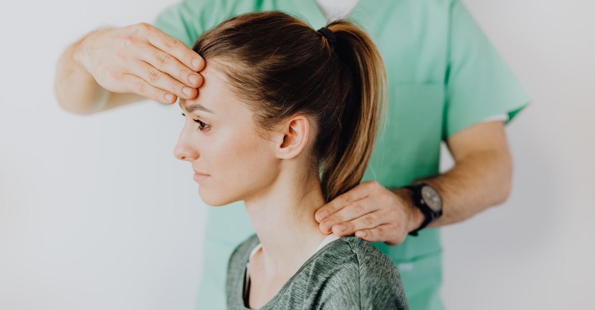 Professional massage therapist performing head and neck massage on content female patient relieving sore neck tensions