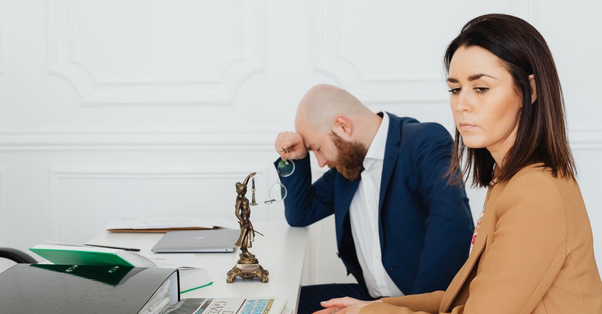 A couple consulting with their lawyer in an office setting, discussing divorce.