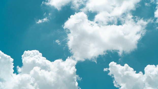A vibrant blue sky filled with fluffy white clouds on a sunny day.