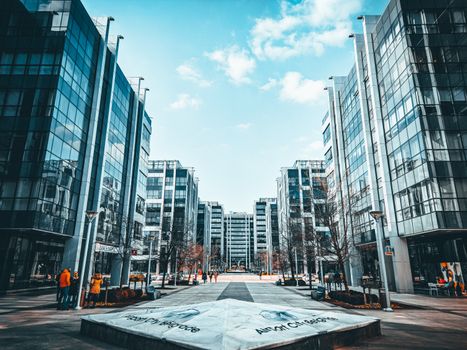 Contemporary urban environment featuring modern glass office buildings along a sidewalk.