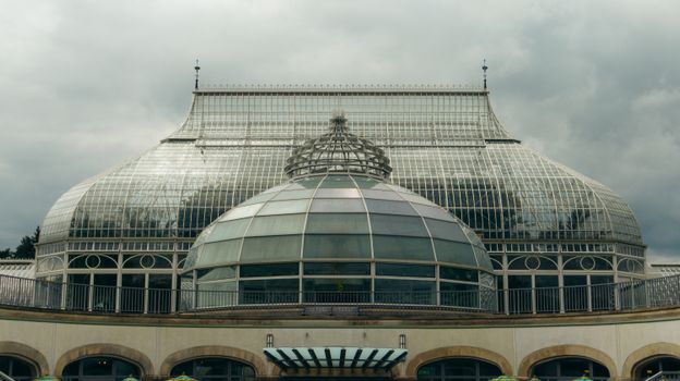 Elegant glass dome of Phipps Conservatory in Pittsburgh on a cloudy day, showcasing classic architecture.