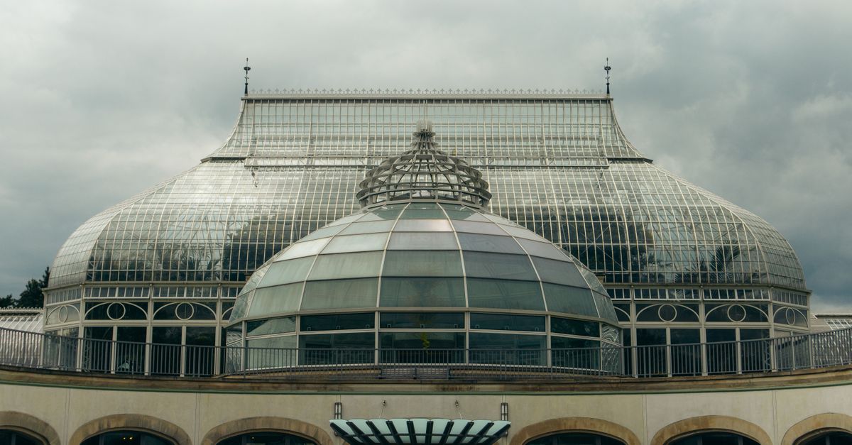 Elegant glass dome of Phipps Conservatory in Pittsburgh on a cloudy day, showcasing classic architecture.