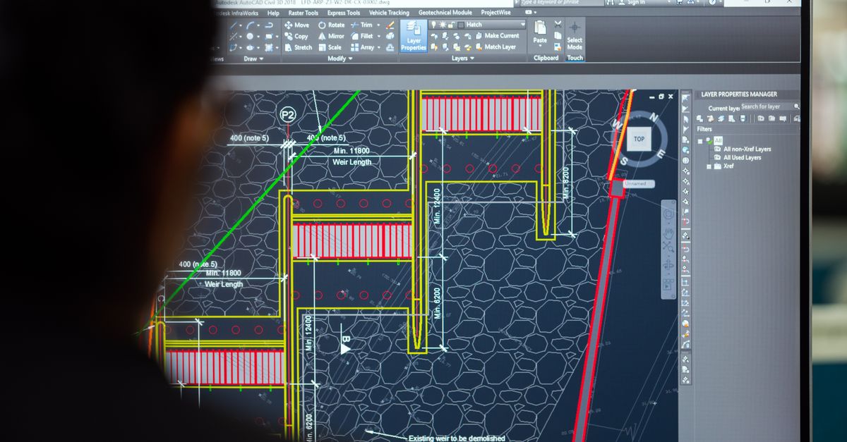 A civil engineer working on a weir design using CAD software on a computer screen in an office setting.