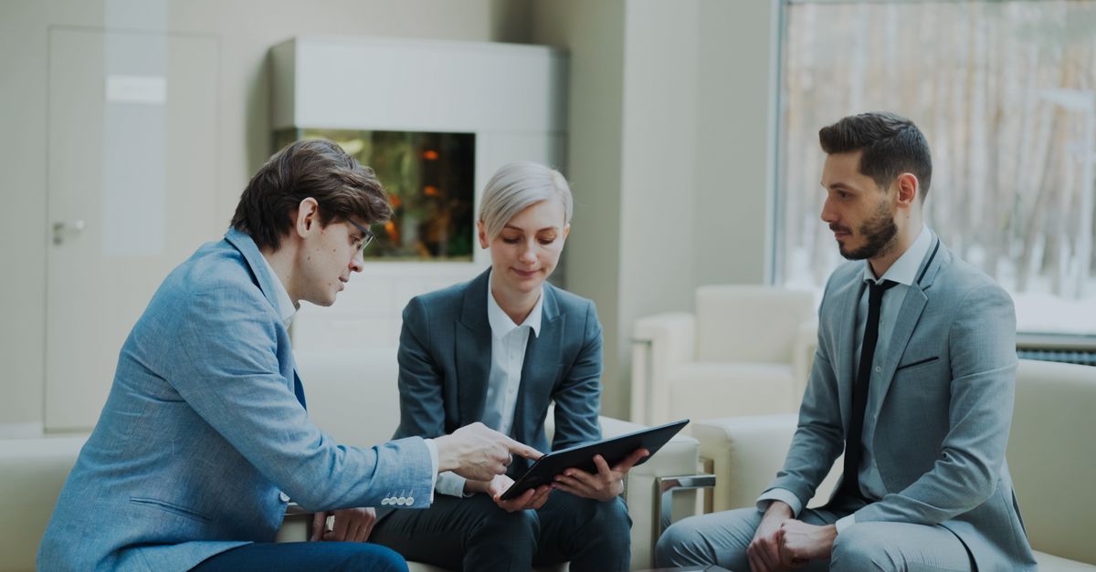 Three professionals engaging in a business meeting in a modern office setting.