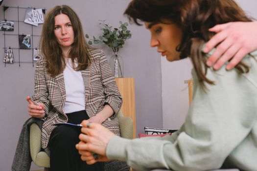 Crop faceless male supporting pondering female with dark hair sharing problems with professional psychologist in daytime